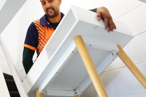 Furniture movers in Christchurch carefully carrying a table during a safe furniture moving service