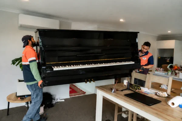 Professional movers in Christchurch carefully moving a piano during a residential relocation